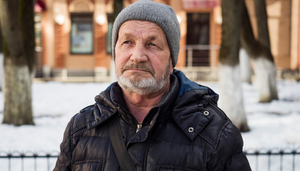 Elderly sad tired man on a city street in winter, real people ev