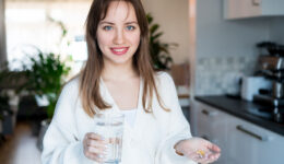 Woman in Her Kitchen Taking Supplements for Health