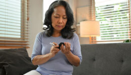 A Woman Sitting On The Couch Measuring Her Blood Pressure Wondering What Are The Warning Signs of Diabetic Ketoacidosis.