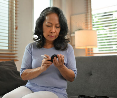 A Woman Sitting On The Couch Measuring Her Blood Pressure Wondering What Are The Warning Signs of Diabetic Ketoacidosis.