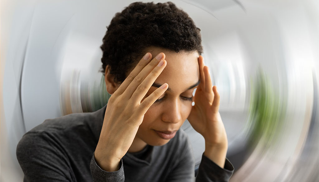 Closeup of an African American Woman Holding Her Head With a Distorted Background Can Sinus Problems Cause Dizziness