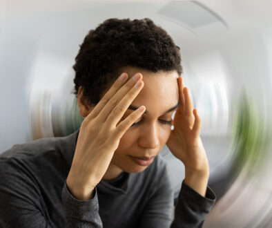 Closeup of an African American Woman Holding Her Head With a Distorted Background Can Sinus Problems Cause Dizziness